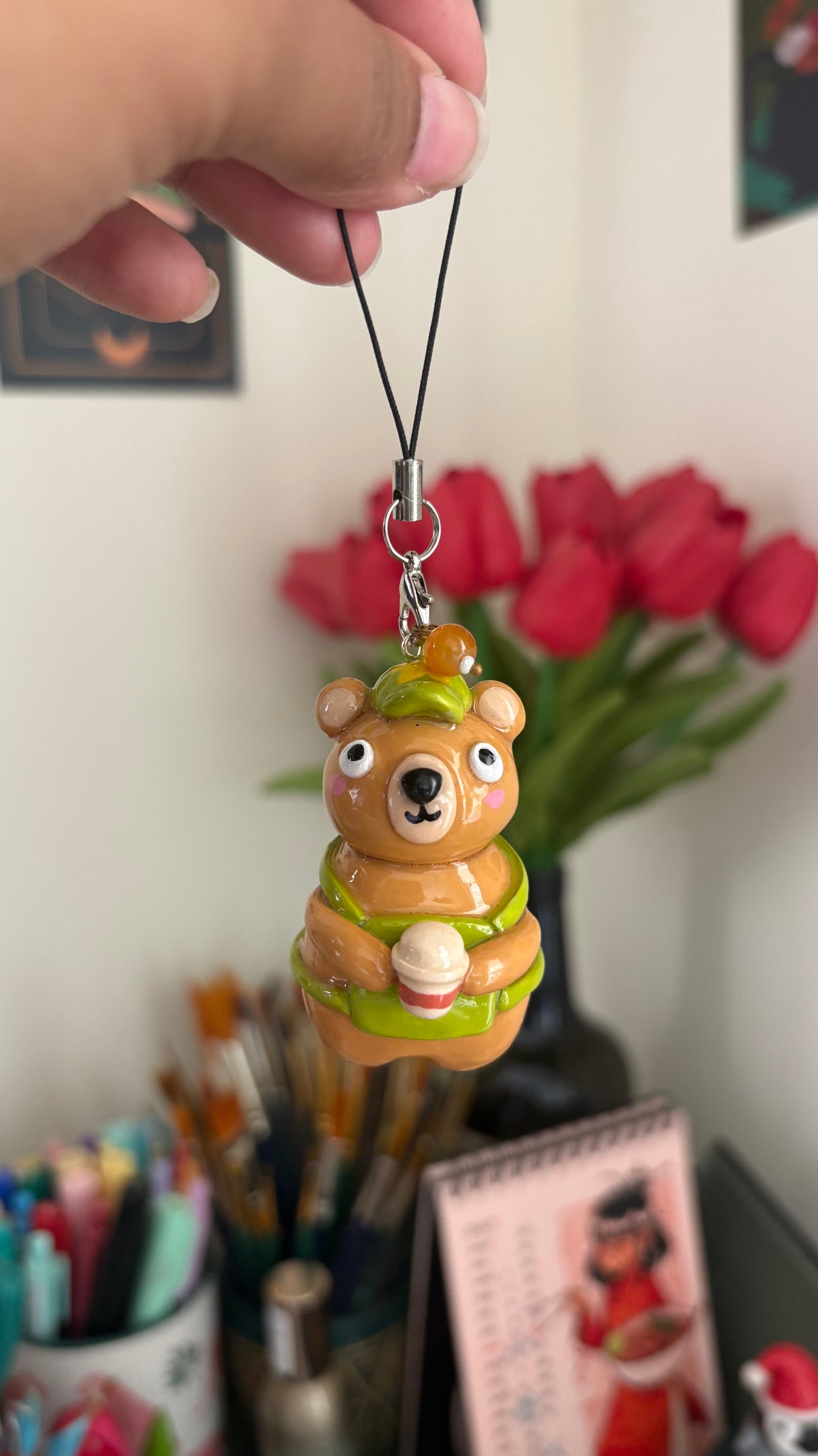 Bearista keychain handmade polymer clay charm, glossy caramel bear in green beret and apron holding a tiny coffee cup, held in hand