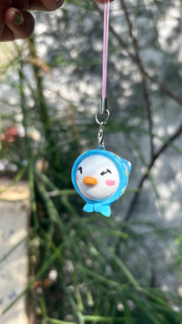 Blue Hooded Bird handmade polymer clay charm, in-hand scale showing small round bird charm with blue hood and orange beak