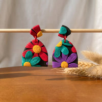 Chroma Flora handmade polymer-clay earrings, displayed on a stand in soft daylight