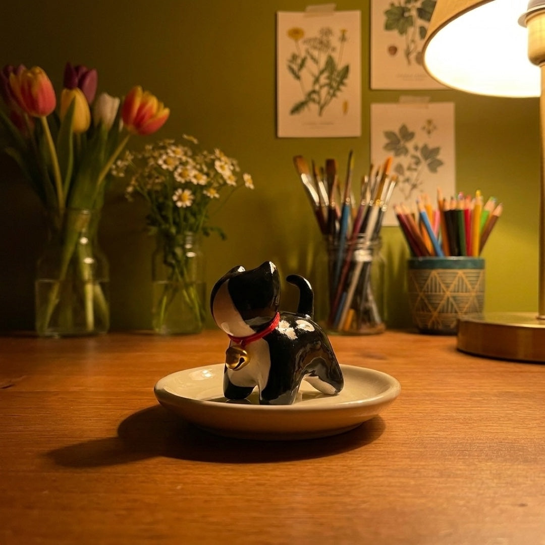 Tuxedo kitty handmade glossy clay desk pal, in the Moon Kiln studio, evening lamp light