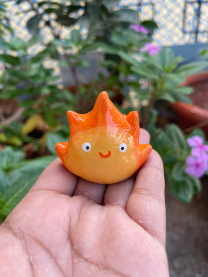 Flame Spirit polymer clay keychain, in-hand scale shot showing glossy orange flame figure with cute rosy expression