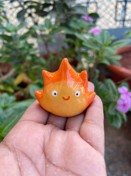 Flame Spirit polymer clay keychain, in-hand scale shot showing glossy orange flame figure with cute rosy expression