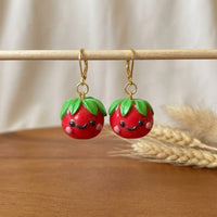 Tomatoes handmade polymer-clay earrings, displayed on a stand in soft daylight