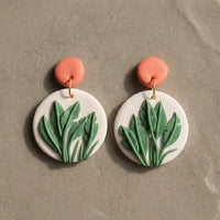 Just Leaves handmade polymer-clay earrings, the pair on a warm stone surface