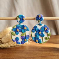 Himalayan Poppies handmade polymer-clay earrings, displayed on a stand in soft daylight