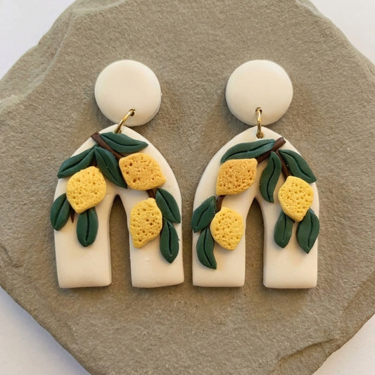Lemon Botanica handmade polymer-clay earrings, the pair on a warm stone surface