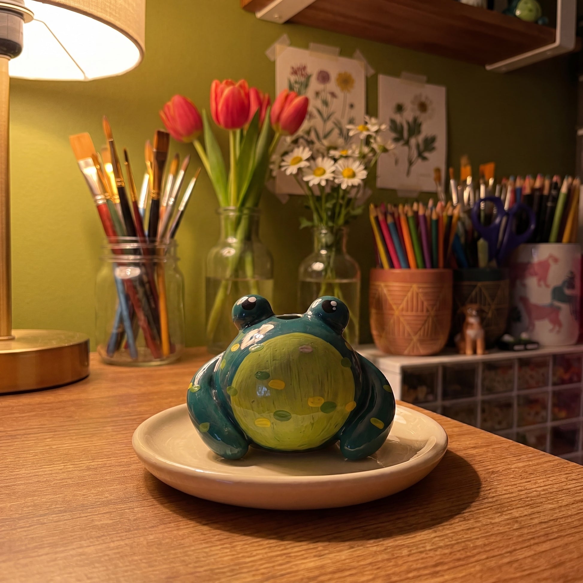 Mr. Ribbit handmade glossy clay desk pal, in the Moon Kiln studio, evening lamp light