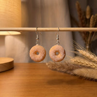 Sugar Donuts handmade polymer-clay earrings, displayed on a stand in warm evening light