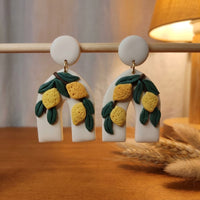 Lemon Botanica handmade polymer-clay earrings, displayed on a stand in warm evening light