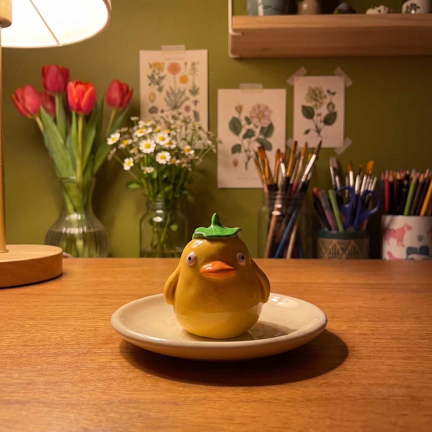 Spirited Ducky handmade glossy clay desk pal, in the Moon Kiln studio, evening lamp light