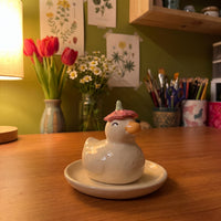 Dreamy Duck handmade glossy clay desk pal, in the Moon Kiln studio, evening lamp light