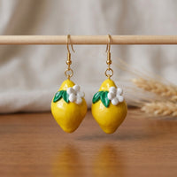 Lemonita handmade polymer-clay earrings, displayed on a stand in soft daylight