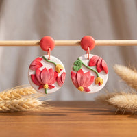 Pink Tipped Lotus handmade polymer-clay earrings, displayed on a stand in soft daylight