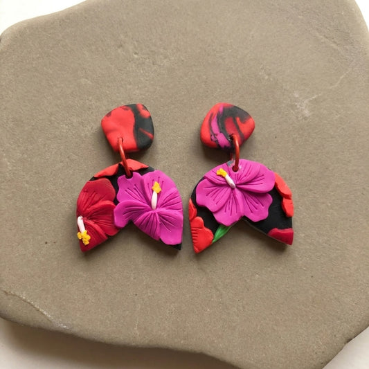 Hibiscus Jungle handmade polymer-clay earrings, the pair on a warm stone surface