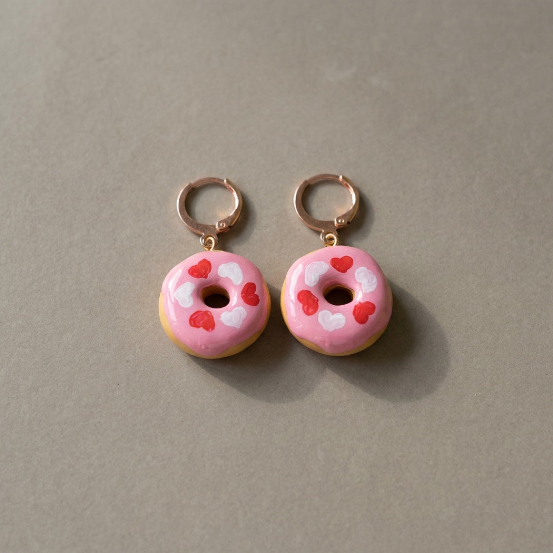 Donut Hearts handmade polymer-clay earrings, the pair on a warm stone surface