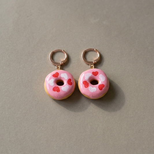 Donut Hearts handmade polymer-clay earrings, the pair on a warm stone surface