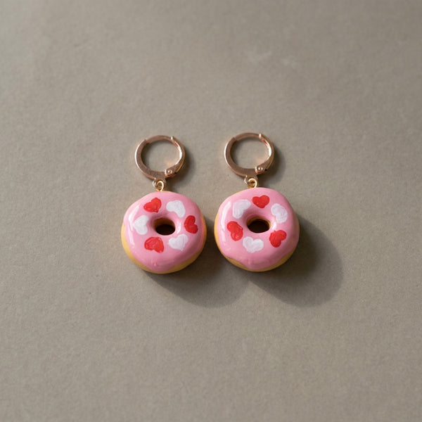 Donut Hearts handmade polymer-clay earrings, the pair on a warm stone surface