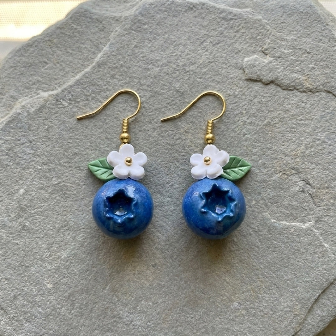 Blueberries handmade polymer-clay earrings, the pair on a warm stone surface