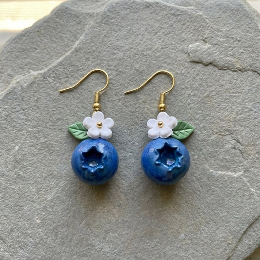 Blueberries handmade polymer-clay earrings, the pair on a warm stone surface