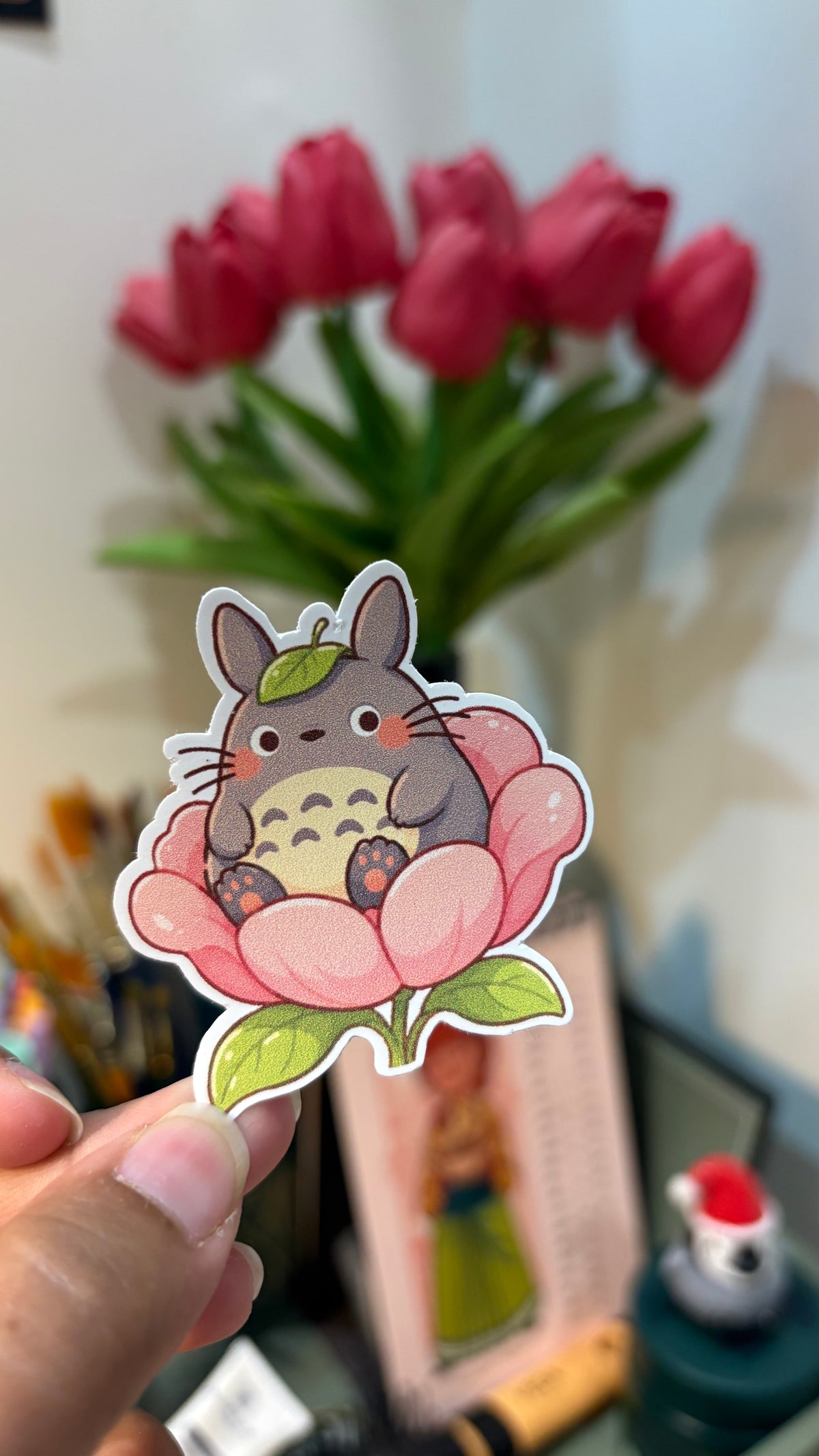 Forest Spirit on a Flower vinyl sticker, round grey forest spirit sitting in a pink peony, held in hand