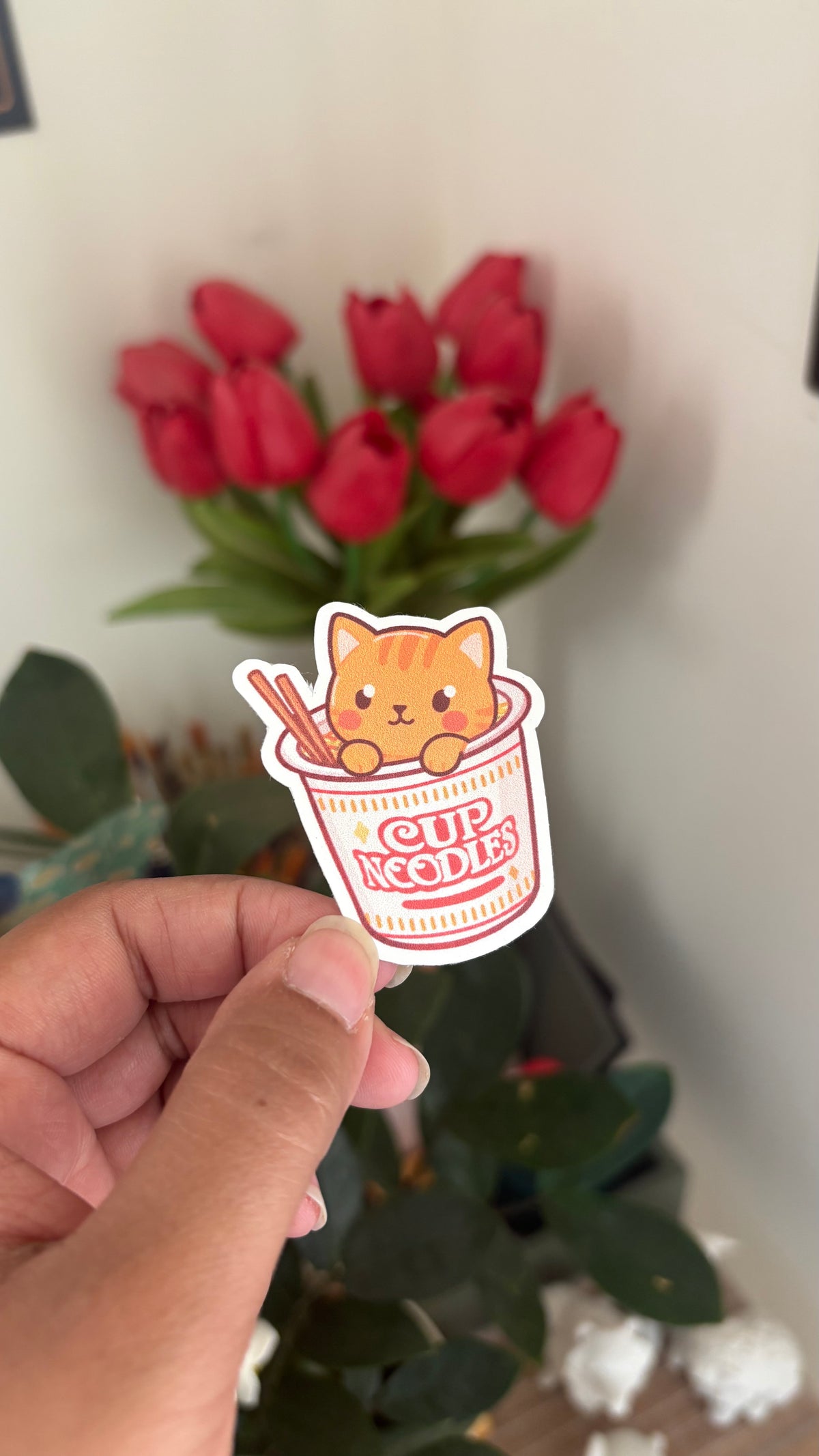 Ginger Kitty Noodles vinyl sticker, orange kitten peeking out of a cup of noodles with chopsticks, held in hand