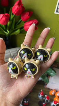 Grumpy Babushka polymer clay charm, in-hand scale shot showing glossy round cat body with floral detail