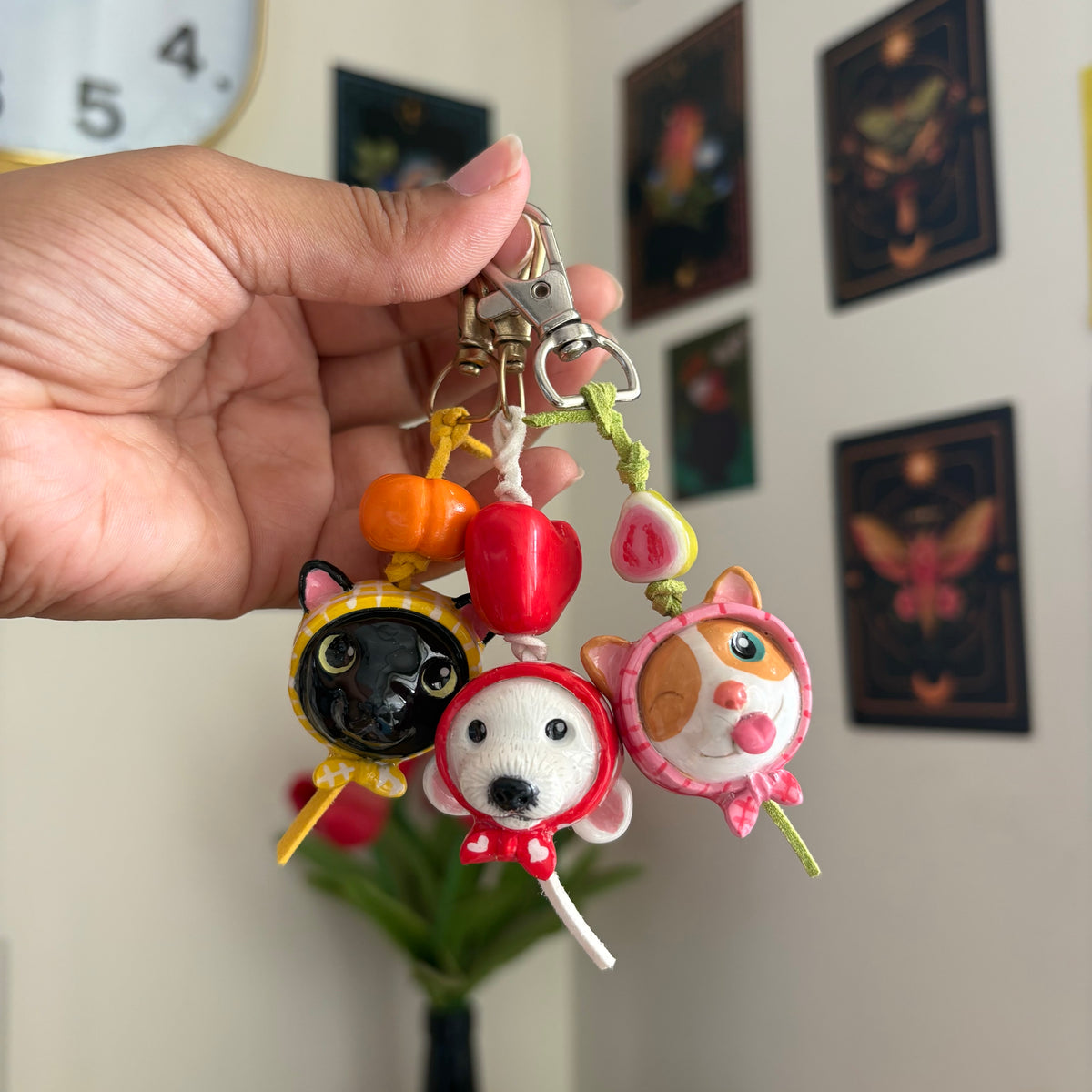 Three hooded clay keychains held up on their clasps