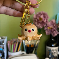 Takoyaki polymer clay keychain, in-hand scale shot showing detailed octopus ball figurine with glossy glaze