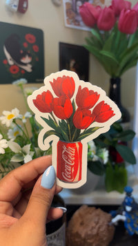 Tulip cola vinyl sticker, in-hand lifestyle shot showing red tulip bouquet sticker against green background